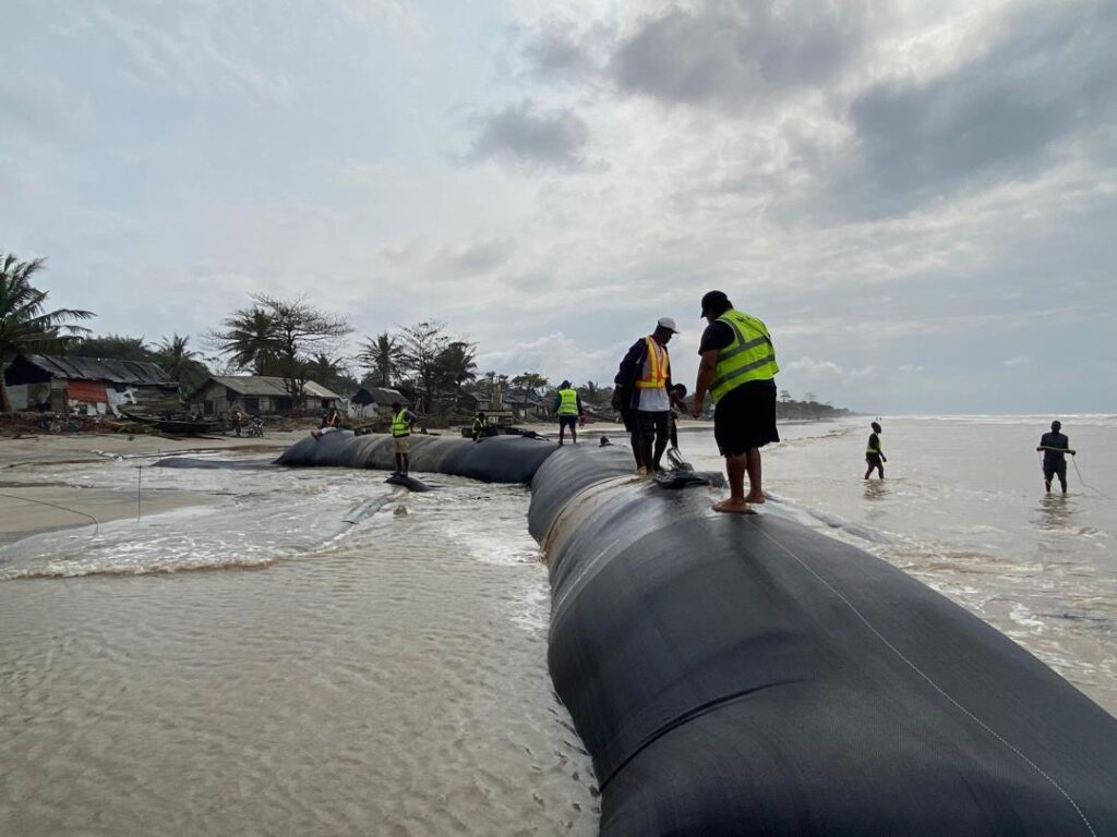 TITANTube® coastal protection — installation crew positioning large tube along eroding African shoreline