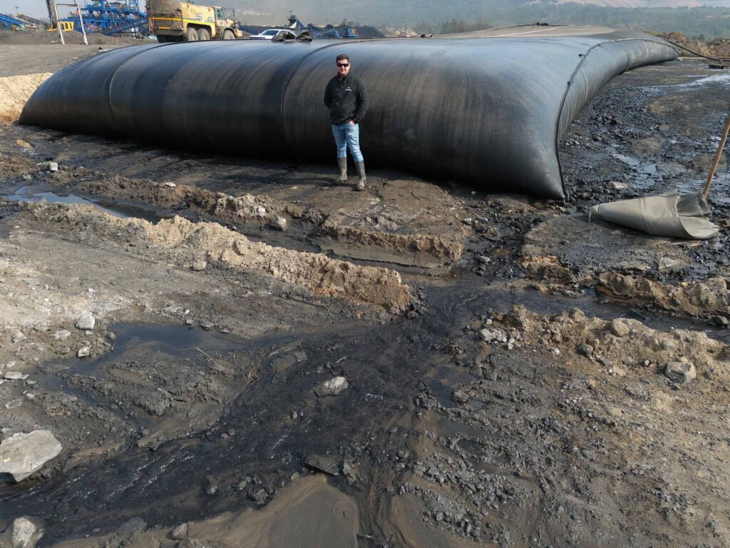 TITANTube® coal mining tailings dewatering — man standing beside filled tube
