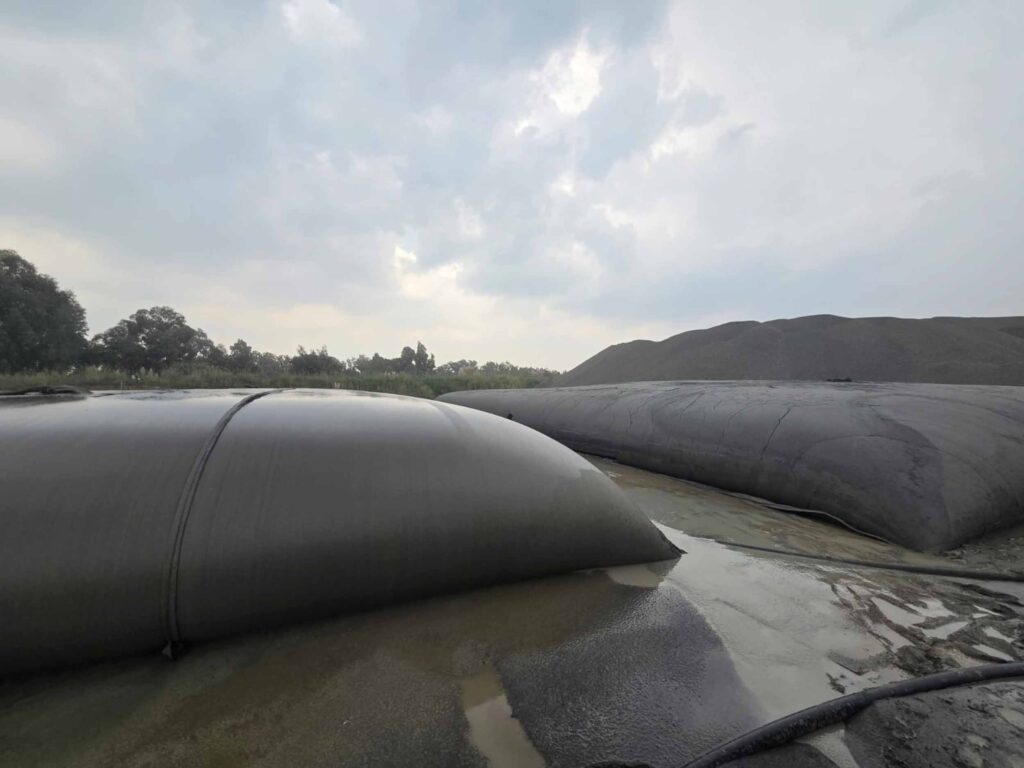 TITANTube® sand washing plant dewatering — large black geotextile tubes with dewatered aggregate stockpile