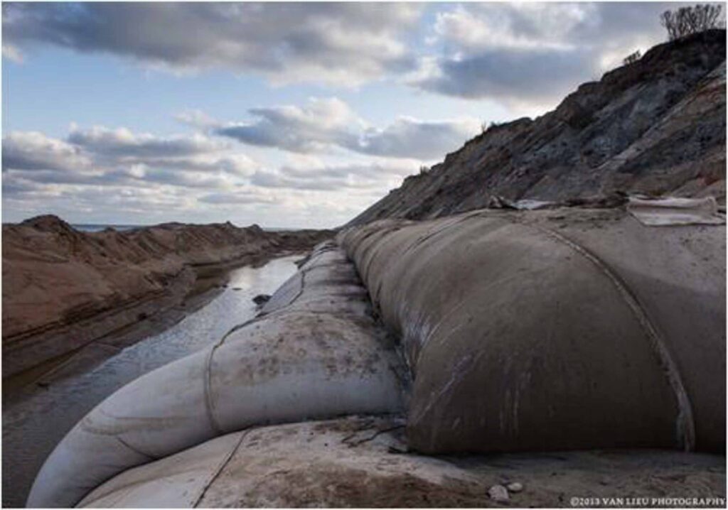 OS435C geocomposite geotextile tube dewatering — tubes alongside sandy embankment