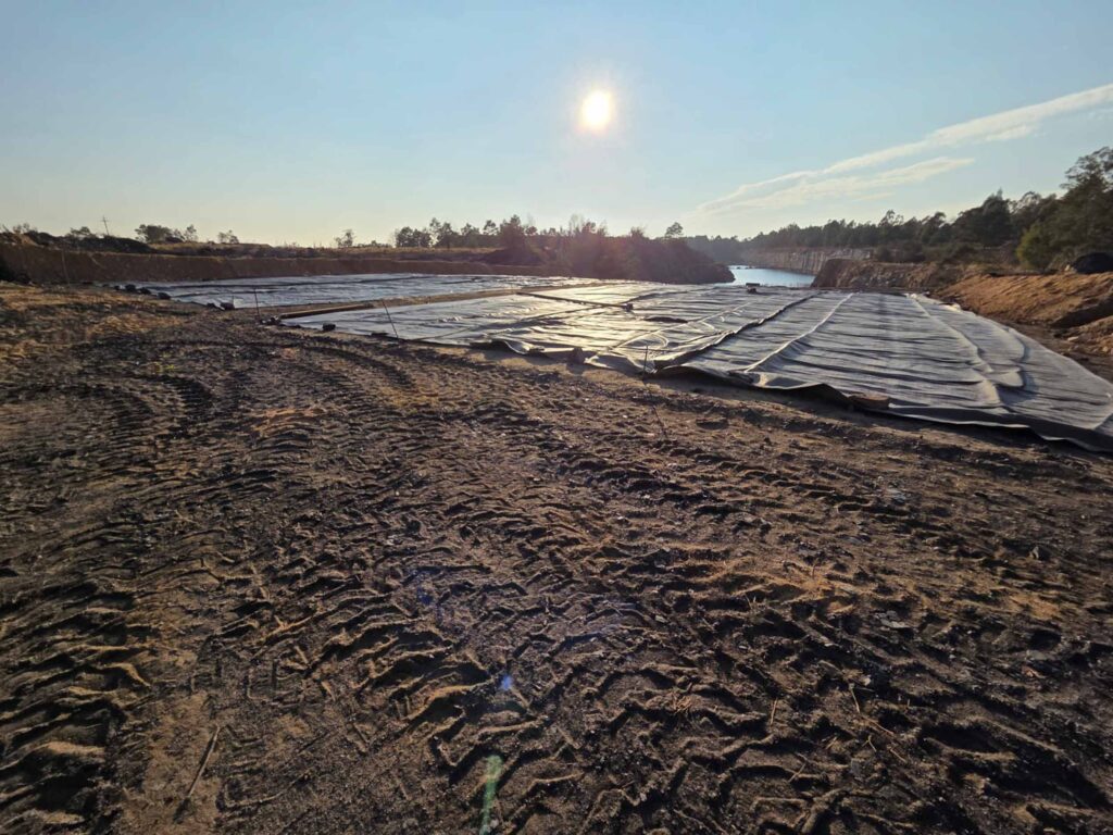 Chromium ore geotextile tube dewatering — flat geotextile panels laid in containment area at sunrise